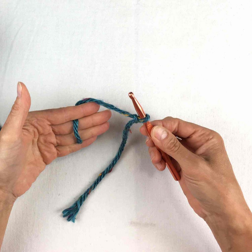 image of hands holding a crochet hook and a slip knot