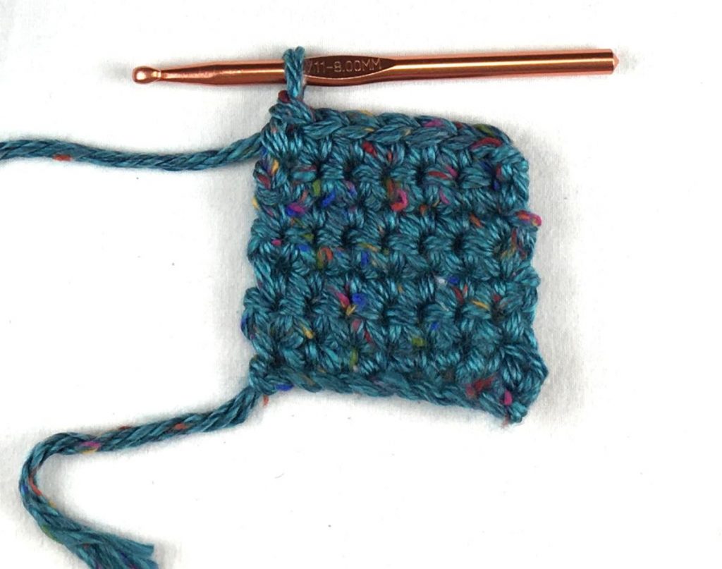 image of rows of crochet with green yarn and a hook