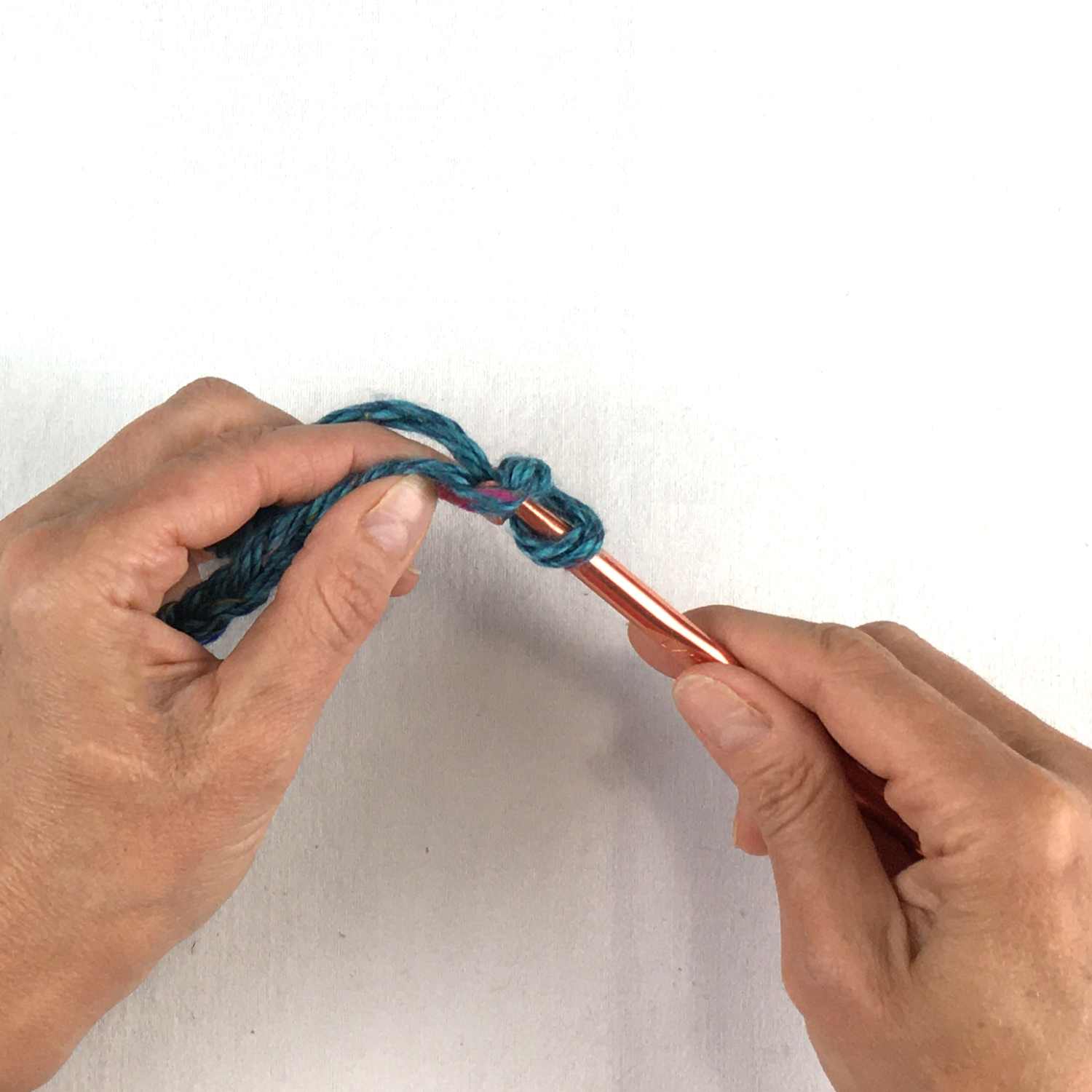 image of hands holding a crochet hook pulling yarn through a loop