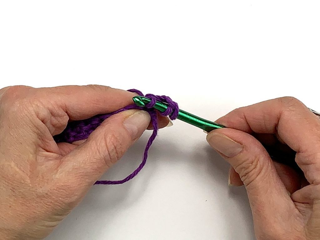 Crochet hook pulling the loop through a stitch