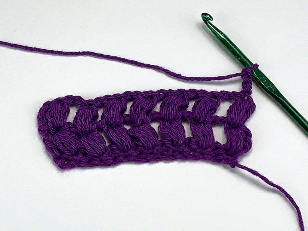 Two rows of crochet puff stitches with purple yarn