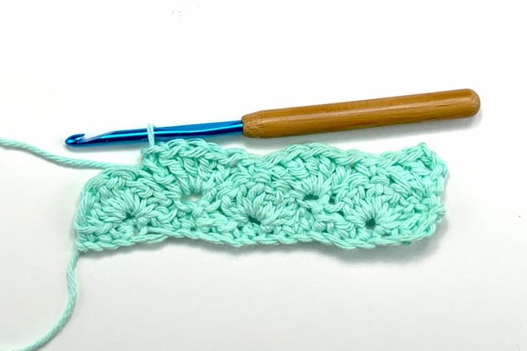 rows of crochet shell stitches in light blue yarn