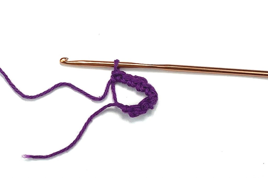 image of a crocheted magic circle and a hook