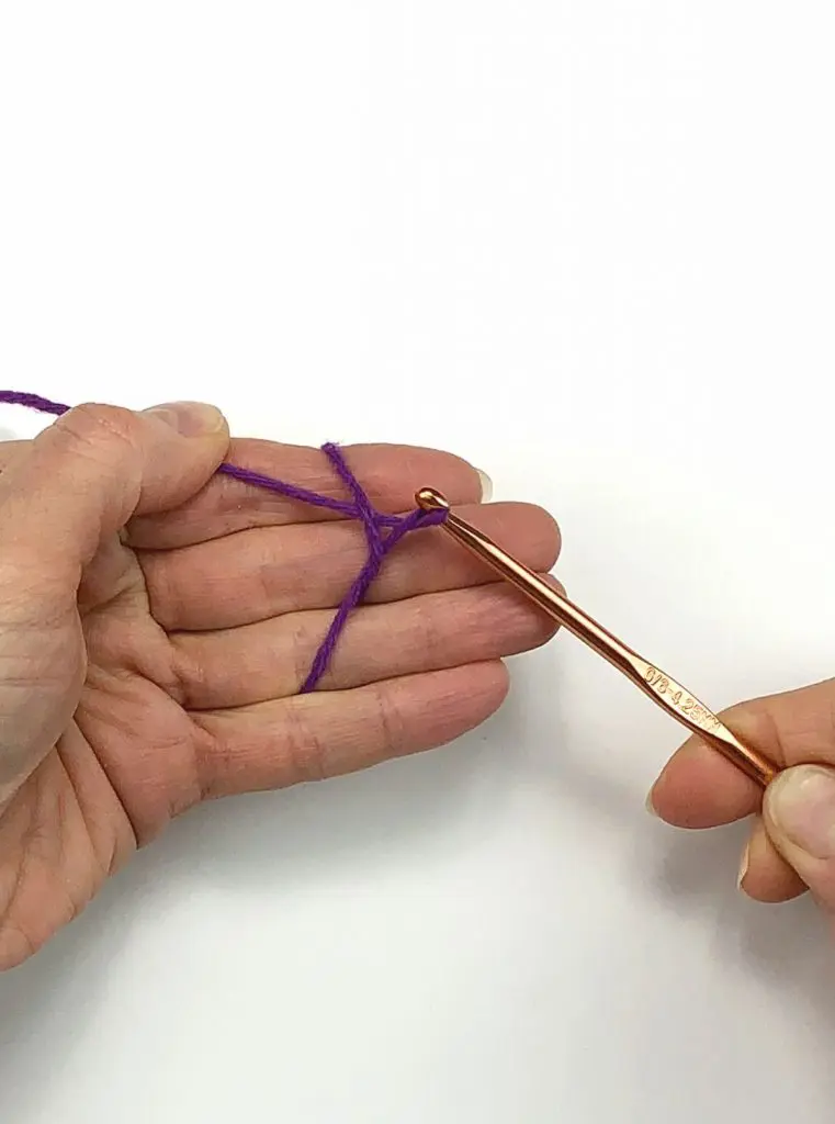 image of a hand working purple yarn with a crochet hook