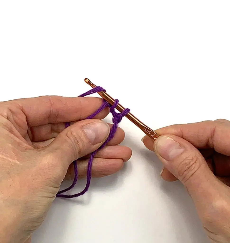 image of hands crocheting purple yarn