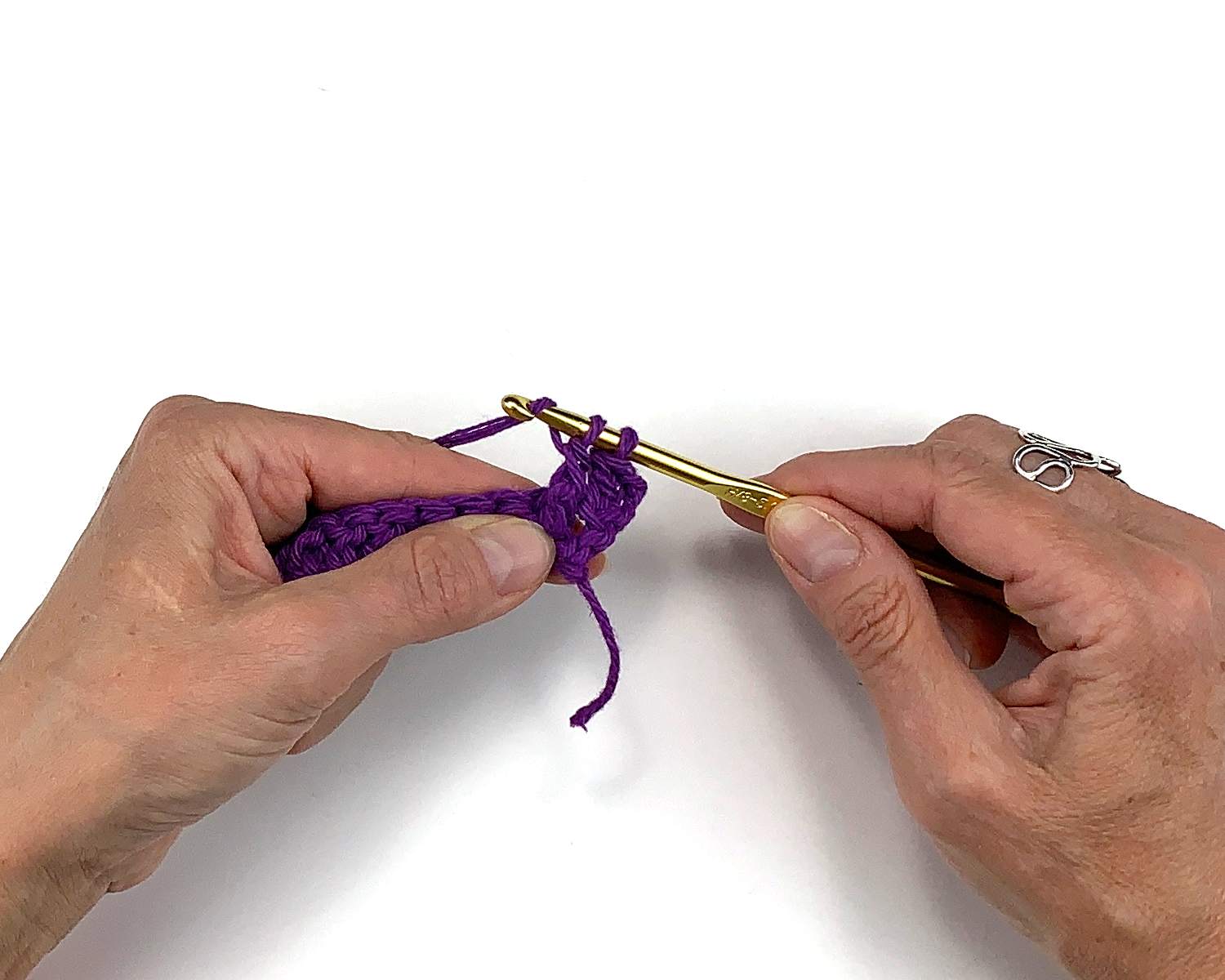 image of hands holding crochet work and doing a yarn over